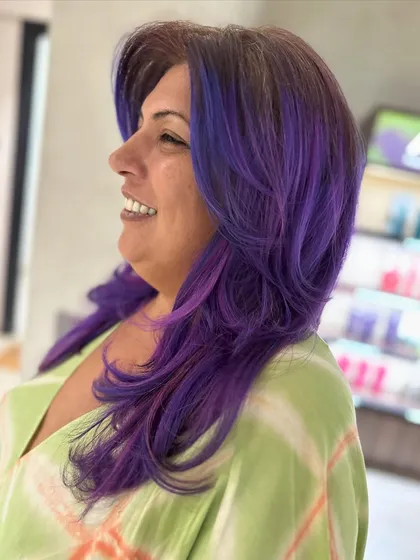 Another bold and beautiful vivid hair color creation. The purple tones are perfectly blended, and the face-framing haircut with curtain bangs adds a stylish edge.