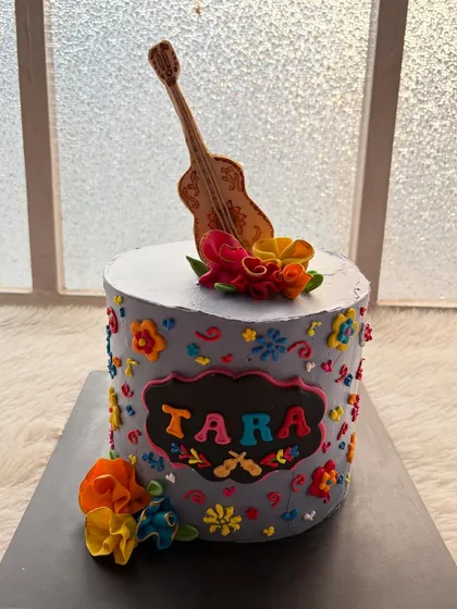 A vibrant cake inspired by the Disney movie "Coco." The design features colorful flowers and a handcrafted guitar, capturing the spirit of the film.