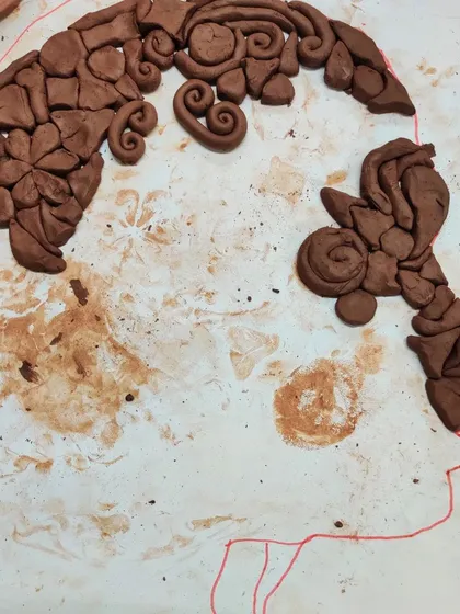 A student's work-in-progress on a clay silhouette. I love seeing how they interpret the project, using different shapes and patterns to create hair and features.