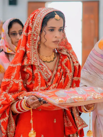 A candid moment during the ceremony. The intricate embroidery on her red dupatta and her elegant gold jewelry are highlighted beautifully in this shot.