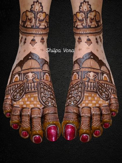 A grand bridal foot design featuring palace architecture and majestic peacocks, with tiny elephant details on the ankle band.