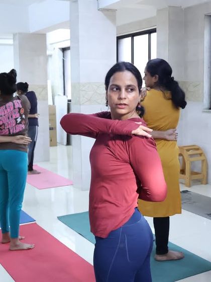 Students practice Gomukhasana (Cow Face Pose) arms, a great shoulder-opening stretch, during an in-person class. I provide individual assistance to help them achieve the correct alignment.