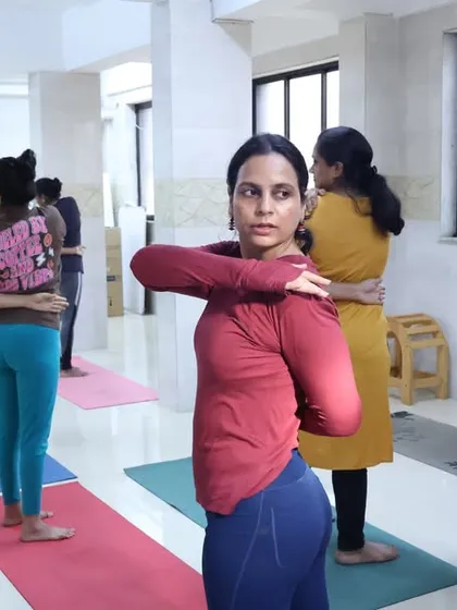 Students practice Gomukhasana (Cow Face Pose) arms, a great shoulder-opening stretch, during an in-person class. I provide individual assistance to help them achieve the correct alignment.