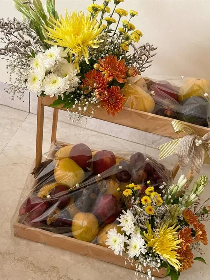 A two-tiered fruit platter decorated with fresh flowers, a healthy and beautiful gift for a wedding celebration.