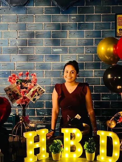 A happy client celebrating her birthday at a cafe. I created this simple yet charming table setup with 'HBD' marquee letters, balloons, and a photo bouquet.