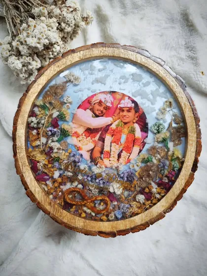 For a more rustic and natural feel, I create keepsakes on beautiful wooden logs. This dreamy frame for my client Divya uses her varmala flowers to create a snow-like effect, highlighting a memory from a special trip and bringing a piece of nature indoors.