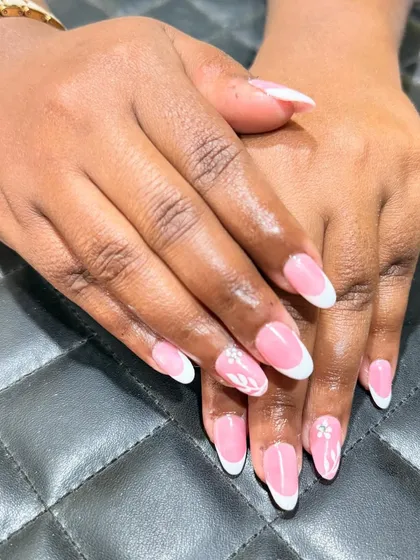 A side view showcasing the elegant curve and shape of these classic French manicure nails. The subtle floral detail adds a personalized touch.