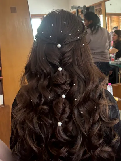 This is a dreamy half-up style with a fishtail braid down the center, accented with large and small pearls. The soft waves and scattered pearls create a magical, ethereal look perfect for a Sangeet or engagement party.