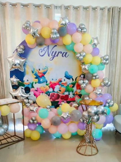 A classic Disney-themed birthday party featuring Donald Duck and friends. This setup uses a custom printed backdrop surrounded by a pastel balloon arch with silver star accents.