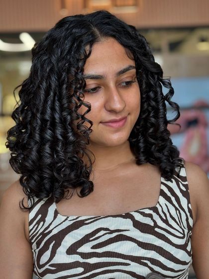 A side profile showcasing the beautiful shape and definition of a fresh curly cut. Each curl is perfectly formed and hydrated, creating a soft yet structured look.