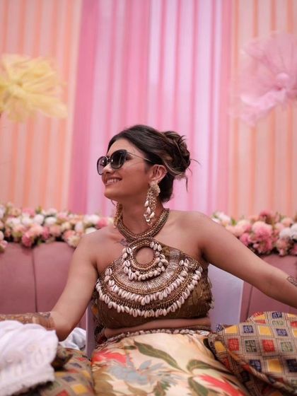 A client enjoying her nature-inspired Mehendi. Her long, shell-detailed earrings were custom-made to complement her unique halter-neck blouse and bohemian theme.