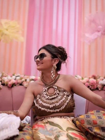 A client enjoying her nature-inspired Mehendi. Her long, shell-detailed earrings were custom-made to complement her unique halter-neck blouse and bohemian theme.