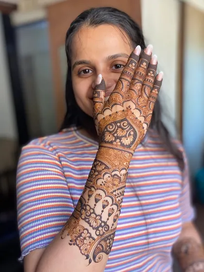 The same happy client, her joy evident as she displays her beautiful henna.