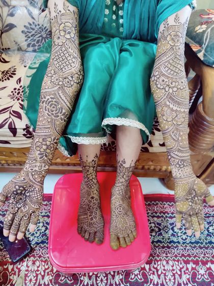 This bride is showcasing her complete mehndi, with full coverage on her arms and feet, ready for her wedding day.