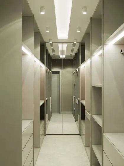 A walkthrough of a custom walk-in closet. The design uses mirrored surfaces and extensive lighting to create a bright and glamorous space, with ample shelving and drawers on both sides.
