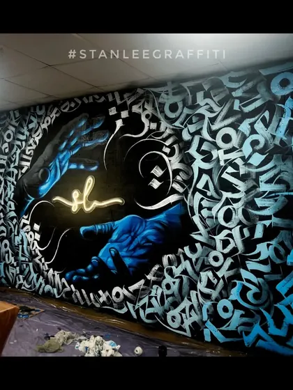 This is my signature calligraffiti style. For this showroom, I blended abstract calligraphy with realistic elements, creating a dynamic piece that wraps around the room. The glowing hands and custom lettering make it a one-of-a-kind installation.