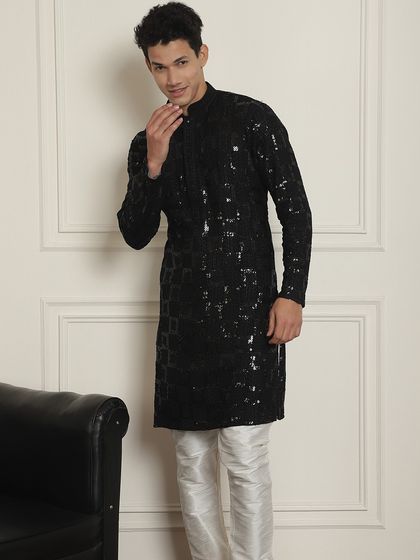A full view of the black sequined kurta, paired with classic white pajamas. It's a glamorous and comfortable choice.