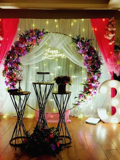 Celebrating 35 years of love with a sophisticated and romantic floral setup. We used a circular arch adorned with purple and pink flowers, sheer drapes with fairy lights, and illuminated numbers to create a magical ambiance for this special anniversary.
