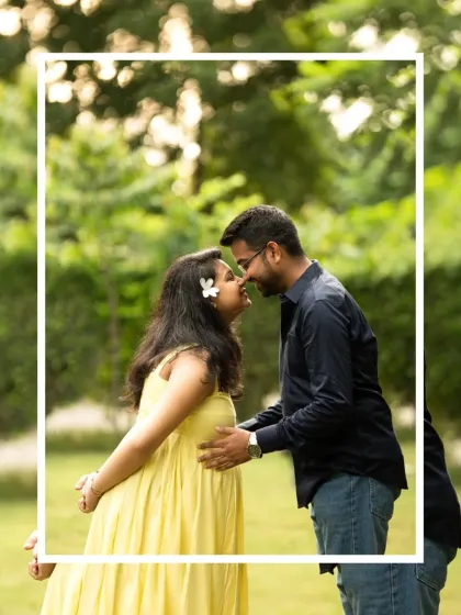 A sweet, intimate moment between a couple during their outdoor maternity shoot. The natural green background and soft light create a romantic and relaxed feel.