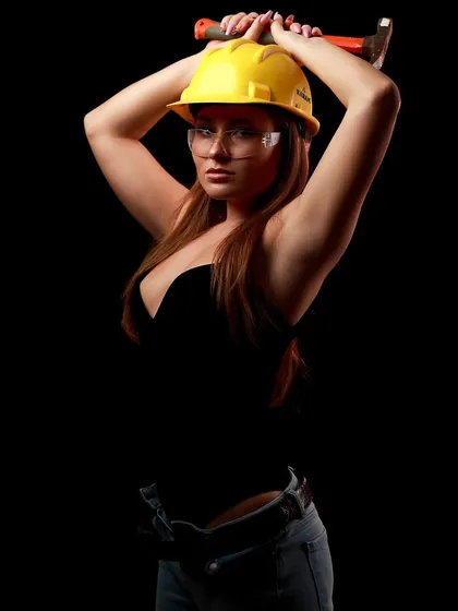 A powerful pose from the worker-themed shoot, with the model holding a hammer above her head.