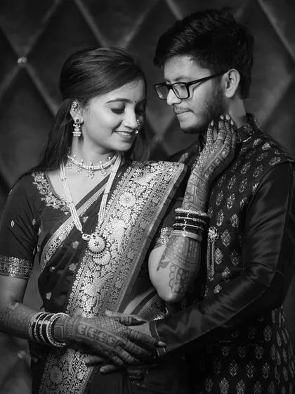 A timeless black and white portrait of the couple. This classic style emphasizes their emotional connection and the intricate details of the bride's saree and jewelry.