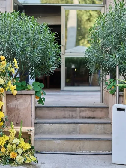 A beautiful entrance detail with rustic wooden crates used as pedestals for lush arrangements of yellow flowers.