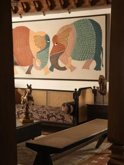A view into the living room, framed by the solid teak pillars. The scale of the artwork is balanced by the strong architectural elements.