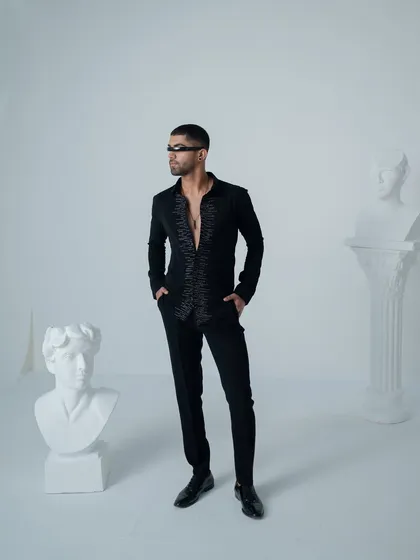This black shirt is elevated with an embellished placket, adding a touch of couture to a classic silhouette. It is an edgy yet refined choice for a cocktail party.