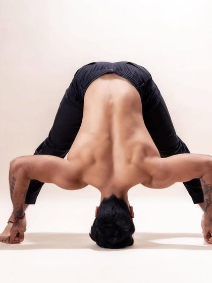 A demonstration of Prasarita Padottanasana, the Wide-Legged Forward Bend. This pose stretches the hamstrings and back while strengthening the legs, preparing the body for deeper forward folds and inversions.