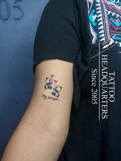 A cute tattoo of two pandas with hearts and the words "my person," a sweet design for a loved one.