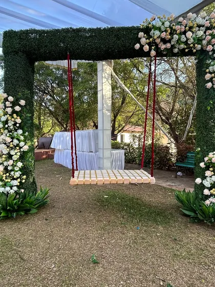 A fun and rustic swing, framed by a green arch and flowers, provides a lovely spot for guests to relax and take photos.
