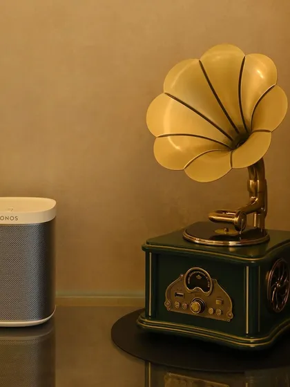 This image beautifully contrasts the old with the new. A modern, wireless Sonos speaker sits beside a vintage-style gramophone, showing how we can integrate the latest audio technology into any decor, respecting classic style while providing modern convenience.