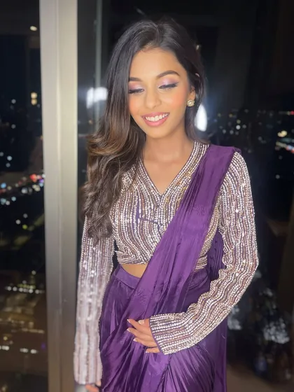 She looks happy and confident. The gentle makeup enhances her youthful features, making her look effortlessly chic in her purple saree.