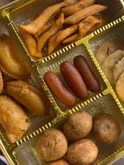 Another view of our popular Rakhi gift box, showcasing the variety of homemade snacks and sweets. We pack gujiya, gulab jamun, mathri, and kachori so you can send a box full of love and flavor.