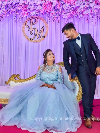 A classic reception portrait. The couple is elegantly dressed, posing on their stage with a custom monogram in the background.