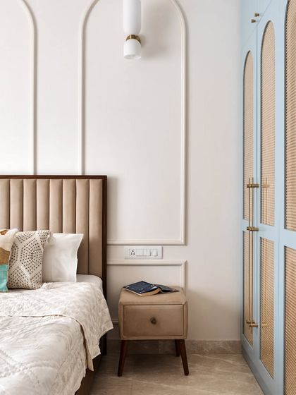 A view of the master bedroom, showing the blue and cane wardrobe next to the bed with its fabric and veneer headboard.