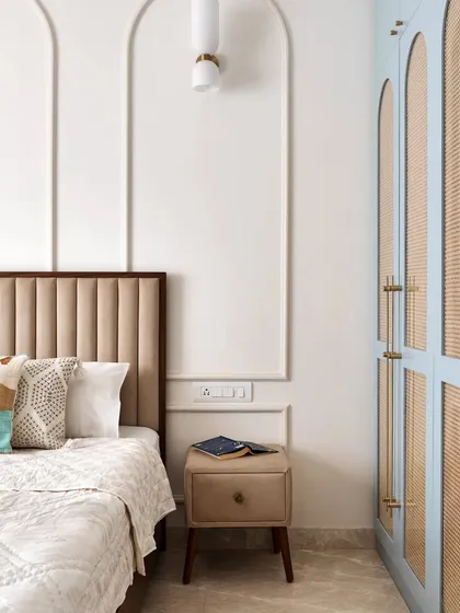 A view of the master bedroom, showing the blue and cane wardrobe next to the bed with its fabric and veneer headboard.
