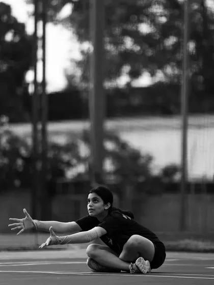 A black and white shot of a player in a low defensive stance, ready to receive. The image captures the raw focus and anticipation of the moment.