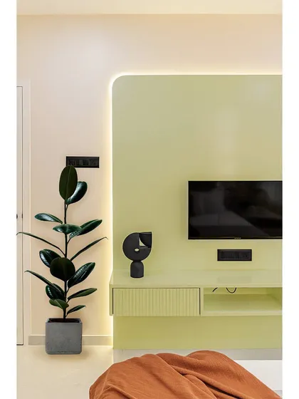A detail of the minimalist TV unit, which features a clean, floating design and subtle fluted details. A single plant adds a touch of life and color.