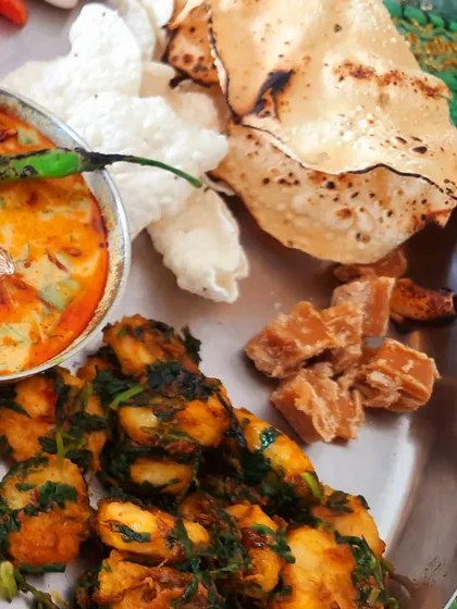 A rustic plate featuring kela methi ki sabzi (banana and fenugreek) and chunks of jaggery. This combination of sweet, savory, and bitter is a hallmark of authentic Gujarati cuisine.
