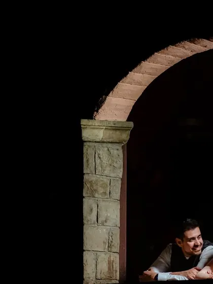 A minimalist portrait where the couple is framed by a dark archway. The use of shadow and negative space creates a mysterious and intimate "stolen moment" feel.