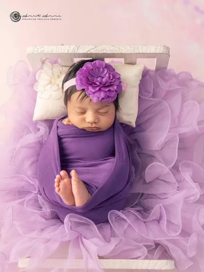A closer look at this sweet baby, wrapped snugly in a purple swaddle with a matching floral headband. The details make the portrait.