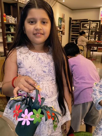 A student proudly holds the paper flower basket she made as a gift for Mother's Day. These handmade gifts are always filled with so much love.