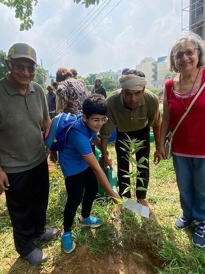 Grandparents and their grandchild plant a sapling together, a powerful example of intergenerational effort in environmental stewardship.