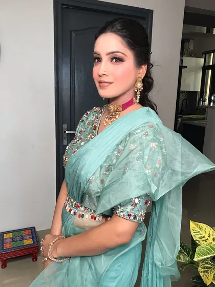 This client is serving glam in a powder blue saree, styled with a unique choker with a pink strap.