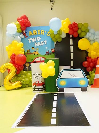A full view of the "Two Fast" birthday backdrop, with a custom sign, road-themed details, and a number "2" foil balloon.