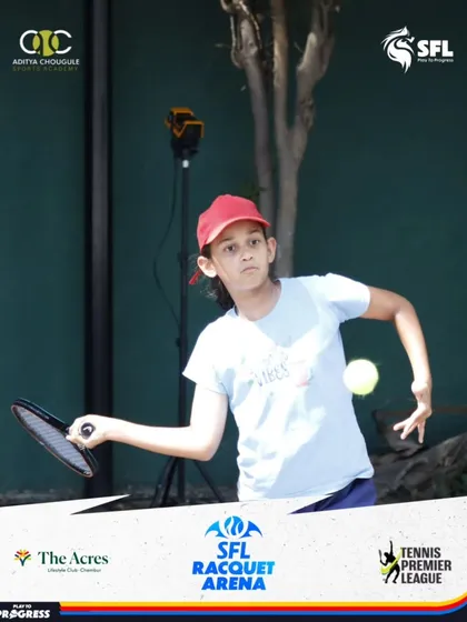 A young girl practices her backhand swing with a specialized training racquet, a tool we use to help develop proper form and muscle memory.