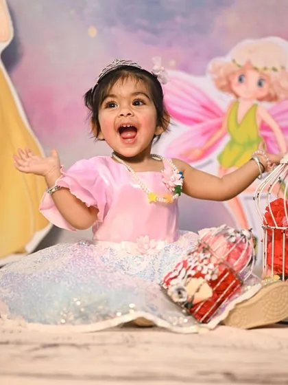 An expressive moment from a fairy-themed photoshoot. The backdrop includes cutouts of other characters like Snow White, blending different fairytale elements for a magical setting.
