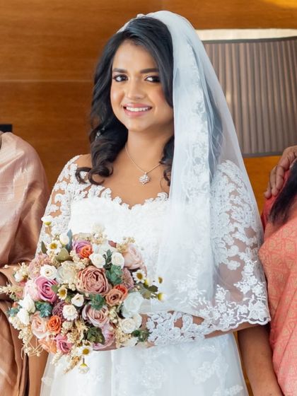 A close-up with her beautiful bouquet. Her smile is radiant, and her makeup is fresh and pretty.