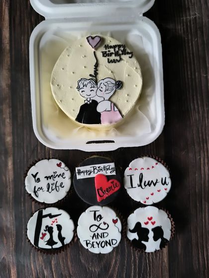 This bento and cupcake set tells a complete love story. The main bento features a hand-drawn couple portrait, while the cupcakes continue the narrative with messages like "To infinity and beyond."